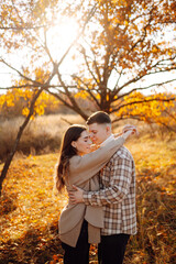 Couple in love rests and walks together in the autumn park. Stylish man and woman enjoy autumn weather. Concept of love, relationships, relaxation.