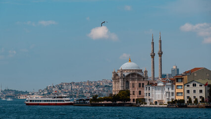 Fototapeta na wymiar View of Ortaköy mosque in the Bosphorus and a flying seagull. The boats standing behind. Istanbul Türkiye