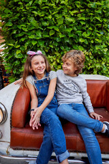 Smiling friendly girl and boy having fun on sofa in city