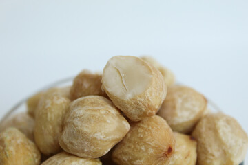 Dried Indonesian Candlenuts, or Kemiri, the seed of Aleurites moluccanus inside a transparant bowl, isolated in white background