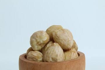 Dried Indonesian Candlenuts, or Kemiri, the seed of Aleurites moluccanus inside a wooden bowl, isolated in white background