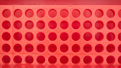 Detalles de agujeros redondos en escurre platos de plastico rojo - obrazy, fototapety, plakaty