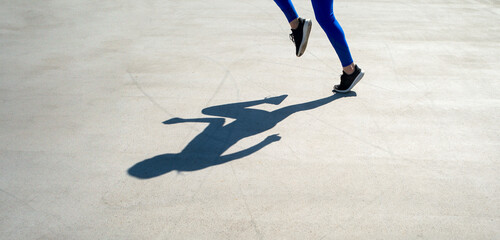 shadow of a woman athlete jogger in road