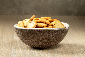 Brown porcelain cup with salted crackers on a wooden table