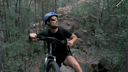 mountain bike.A man in a protective helmet and glasses stopped on rough terrain and looks away.Active lifestyle