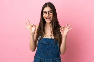 Young caucasian woman isolated on pink background showing ok sign with two hands