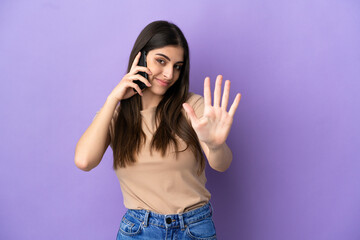 Young caucasian woman using mobile phone isolated on purple background counting five with fingers