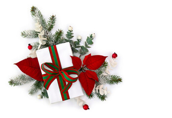Christmas decoration. Gift box, red poinsettia flowers, Christmas tree branch, red berries on a white background. Top view, flat lay