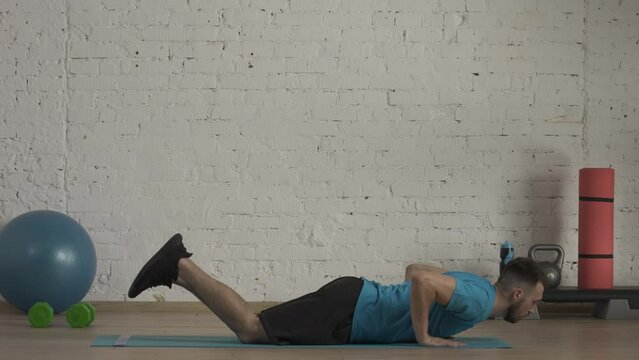 Closeup shot. Man fitness coach in sportswear doing knee push ups exercise for online class at the home studio. HDR BT2020 HLG Material.