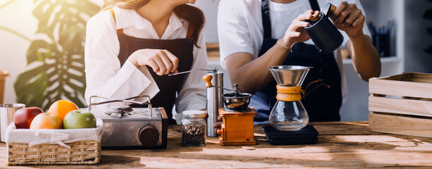 Happy young adult couple making breakfast and drinking coffee together in cozy home kitchen in morning at home. Preparing meal and smiling. Lifestyle, leisure and Love concept.