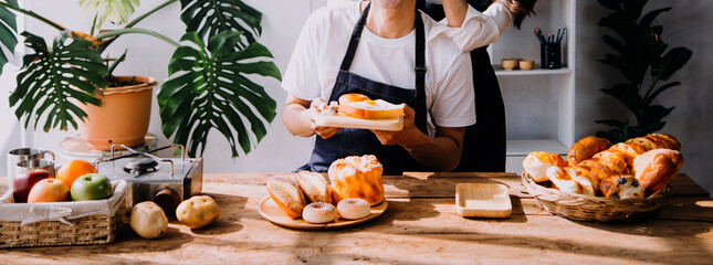 Happy young adult couple making breakfast and drinking coffee together in cozy home kitchen in morning at home. Preparing meal and smiling. Lifestyle, leisure and Love concept.