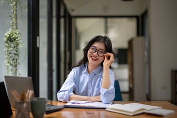 Portrait of smiling businesswoman in eyeglasses sitting at table in office