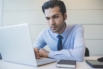 Fototapeta premium Young millennial indian businessman working office