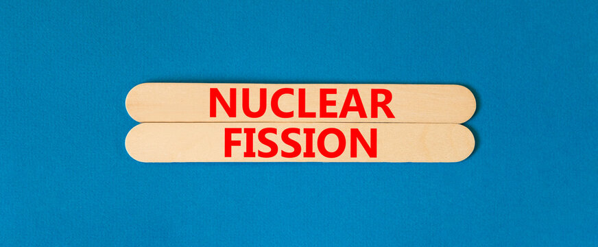 Nuclear fission symbol. Concept words Nuclear fission on beautiful wooden stick. Beautiful blue table blue background. Business science nuclear fission concept. Copy space.