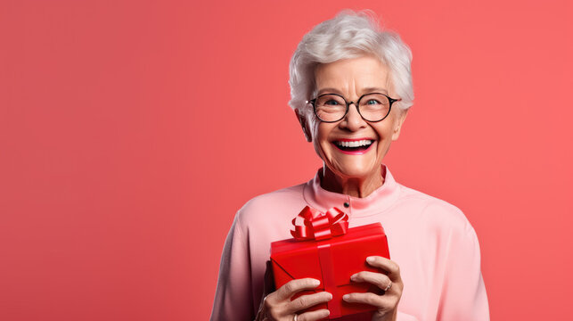 Happy Smiling Senior Woman Holding Gift Box Over Red Background