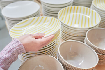 Young woman shopping handcrafted ceramic tableware and utensils in a craft shop. Pottery store concept.	