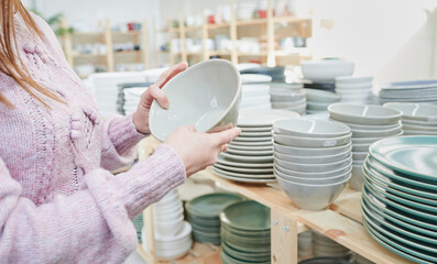 Young woman shopping handcrafted ceramic tableware and utensils in a craft shop. Pottery store concept.	