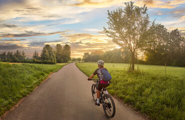 Obraz premium nice woman with electric mountain bike, cycling in moody morning light on the Neckar valley bicycle path near Ludwigsburg, Baden Württemberg, Germany