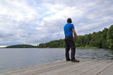 Fisherman at a lake with a blue shirt. Evening photo. Mälaren, Sweden, 2023.
