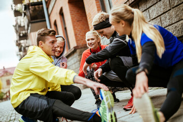 Young group of friends stretching before running and jogging together in the city during colder weather in the winter and autumn months