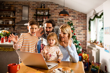 Young family having a video call on their laptop during christmas and the new year holidays
