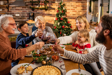 Multigenerational caucasian family having a christmas and new year dinner at home with a christmas tree in the background