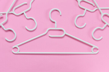 White plastic hangers on a pink background. Concept for sale, shop, second hand, online trade, brand resale platform