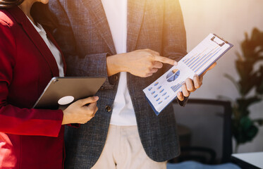 Entrepreneur Asian businessman and businesswoman discussing new business project in tablet in modern Meeting In Modern Office, Asian business casual concept.