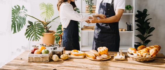 Happy young adult couple making breakfast and drinking coffee together in cozy home kitchen in morning at home. Preparing meal and smiling. Lifestyle, leisure and Love concept.