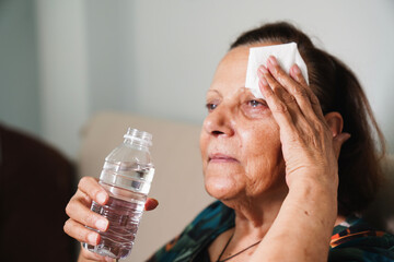 senior woman sweating suffering heat stroke at home