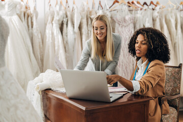Tailor and designer talk to a costumer in a video call about wedding dress request.