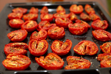 Close-up of sweet and crunchy tomatoes with Provence herbs, vegetables baked on a baking sheet. Selective focus