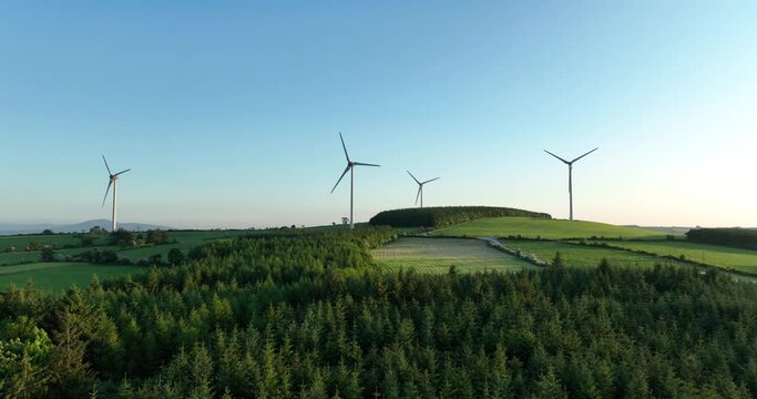 A wind farm for energy production against a backdrop of beautiful green fields