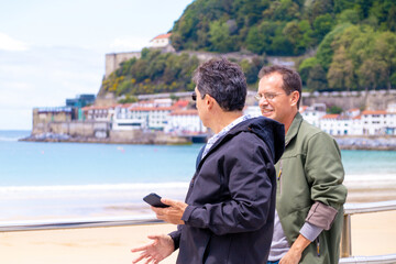 Fototapeta premium Two men walking looking at the sea in springtime