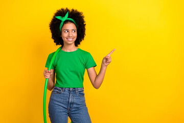 Photo of charming teen schoolgirl hold hula hoop look direct finger empty space isolated on yellow color background