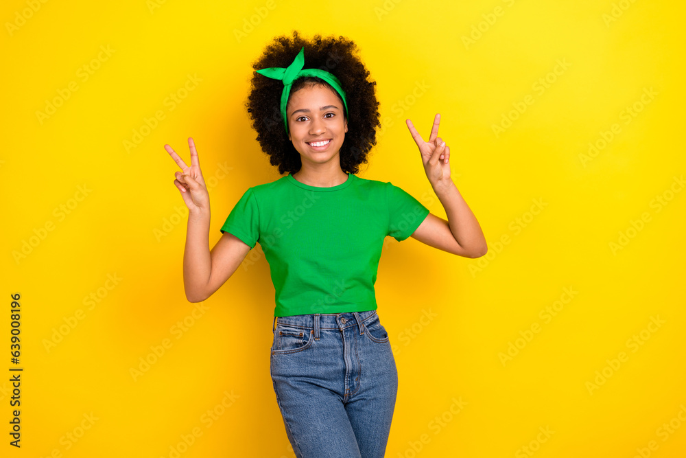 Wall mural Photo of charming cute lady wear green t-shirt hairband showing two v-signs isolated yellow color background