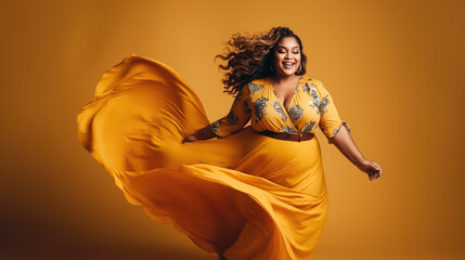 Lucky plus-size lady overweight woman in fashion orange dress happy dancing, celebrating on yellow background with free text space