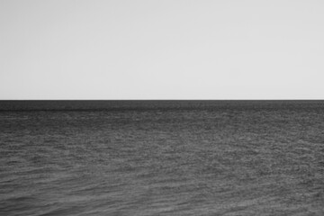 Looking out over the water in a minimalist view with a sky and horizon line in black and white.