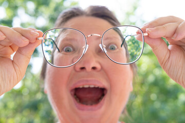 surprised woman in glasses looks in surprise, funny joke, female joker laughs with mouth wide open,...