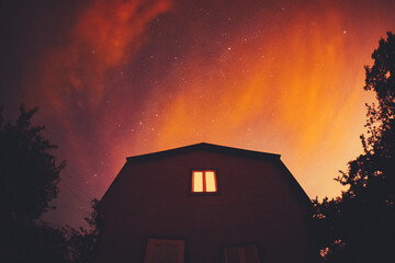 Mysterious house with one window against the background of a starry red sky