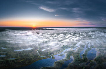 Colorful morning sunrise over the bog of national park of Ķemeri. Wooden trail leading through wetlands covered in fog. 
