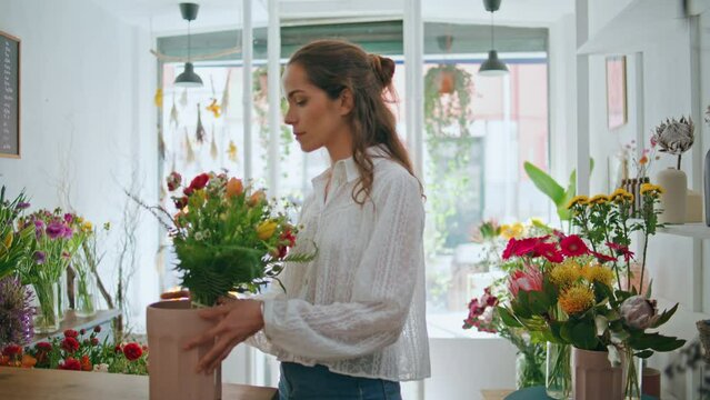 Beautiful florist look camera at flower workplace job. Joyful girl work in shop.
