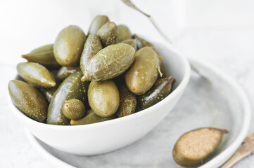 capers in white dishes on a light background. Pickled capers. Canned capers. Close-up