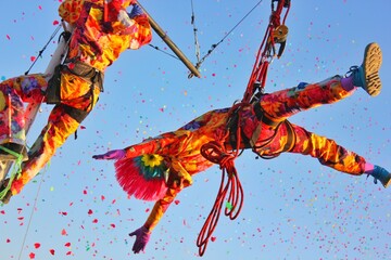 A man in a beautiful punk acrobat costume in the air on a rope in flight performs tricks and poses...