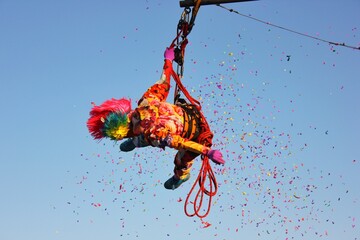 an acrobat in colored clothes in the air against the background of the sky and confetti. real...