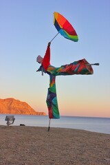 An unusual photo of a man in a colorful rainbow suit walking along the seashore. A man in carnival...