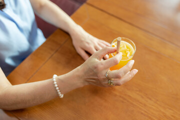 woman hands holding a glass with orange juice and a straw