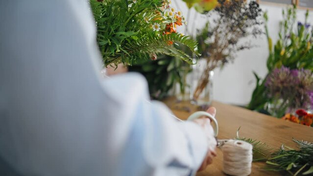 Closeup florist hands make bouquet flower decoration on plant shop sale delivery