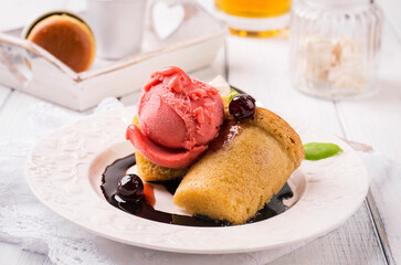 Traditional French rhum baba with cherry ice cream and amarena sauce served as close-up on a classic design plate