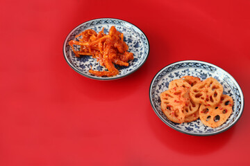 赤背景の皿に盛り付けたスルメキムチキムチと蓮根キムチ